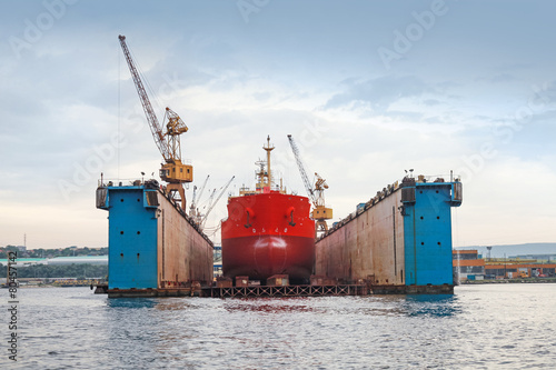 Floating blue dry dock with red tanker under repair