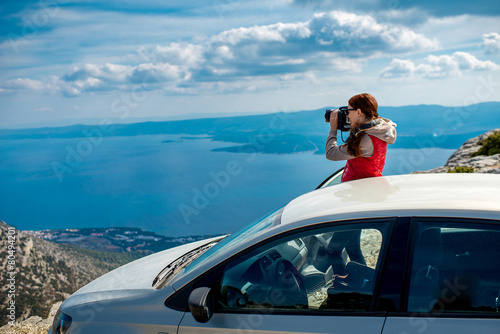 Woman photographer with car on the top of mountain