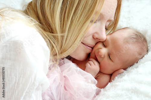 Happy Mother Snuggling Newborn Baby in Bed