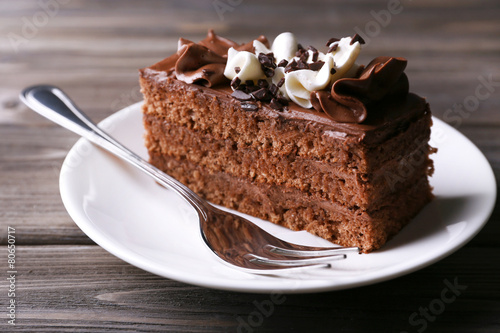 Tasty piece of chocolate cake on wooden table background