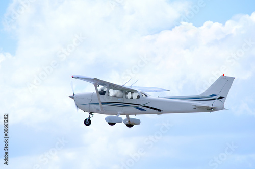 Small private single engine airplane in flight with clouds