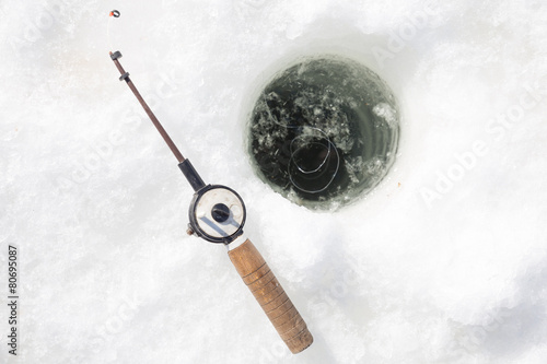 Hole with water and small rod for winter fishing
