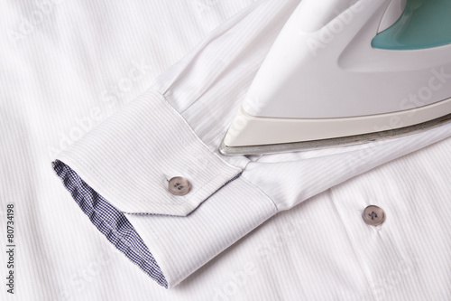 close up of iron ironing sleeve of cotton shirt