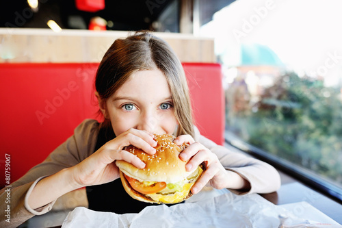 Cute little girl eating a hamburger