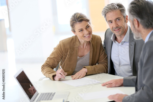 Mature couple signing financial contract at the bank