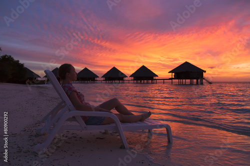 Girl on a deck chair enjoying the sunset in the Maldives