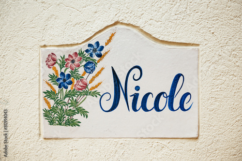 Nicole - old tile on city street wall with flower and beautiful