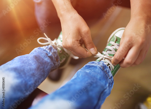 Father tying shoe laces of his son traveling in train.