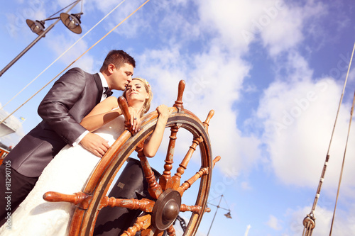 Bride and groom holding old boat steering wheel