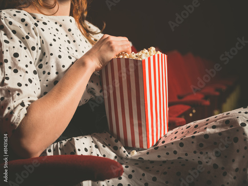 Young woman eating popcorn in movie theater