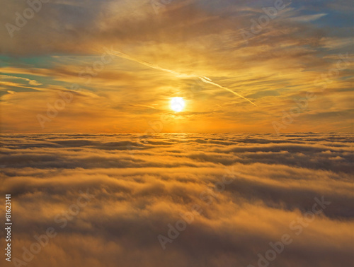 Golden sunset sky view above clouds during airplane flight
