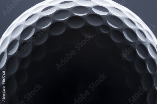 Macro shot of golf ball with light and shadow.