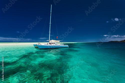 White catamaran in shallow tropical water with snorkeling reef