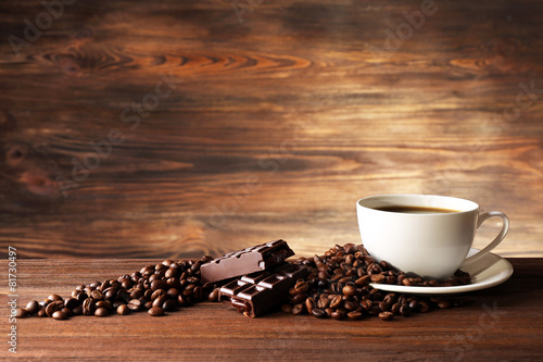 Cup of coffee with grains on wooden background