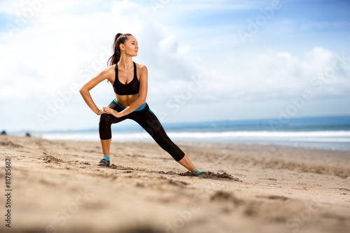 Fit woman doing exercises for legs on the beach