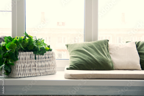Pillows on the windowsill and plastic window. Wicker basket with