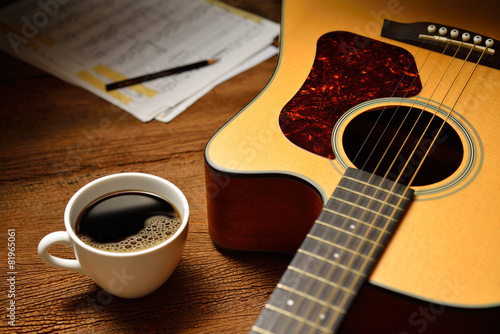Cup of coffee and guitar on wooden table
