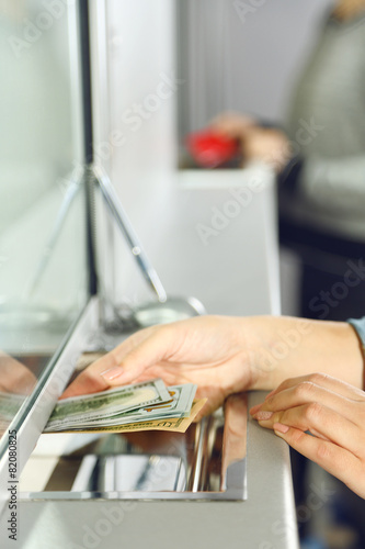 Female hand with money in cash department window. Currency exchange concept