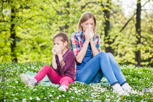 Two people with allergy symptom blow their noses