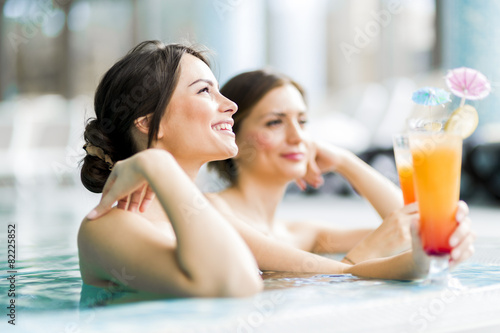 Beautiful young women drinking a cocktails in the swimming pool