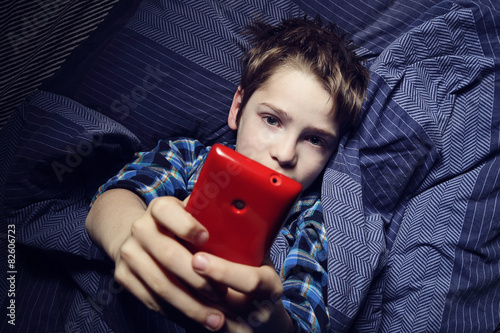 enfant garçon au lit avec smartphone