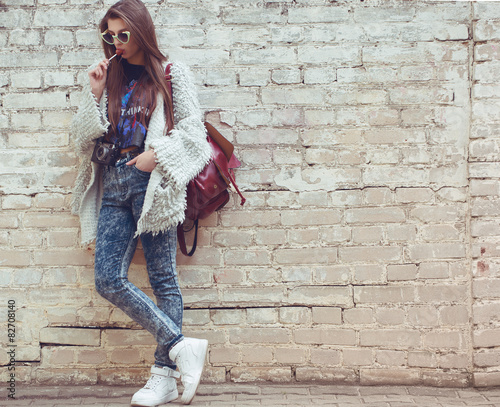 Young street fashion girl on the background of old brick wall