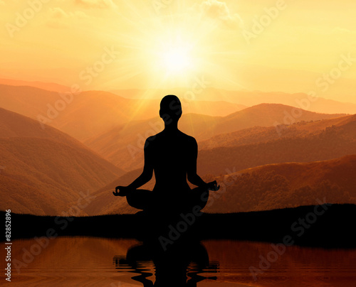  Man meditating in yoga position on the top of mountains