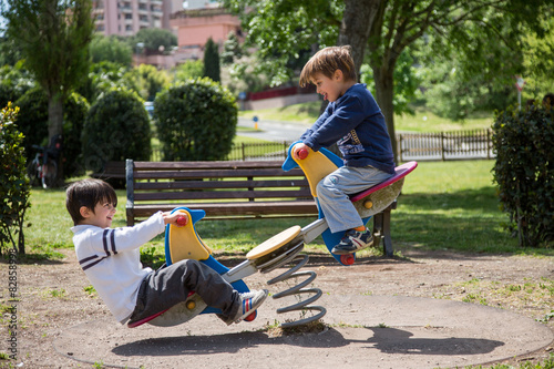 Coppia di bambini che giocano sul dondolo a molla