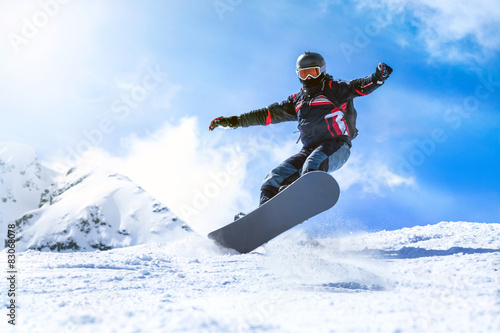 Jumping snowboarder from hill in winter