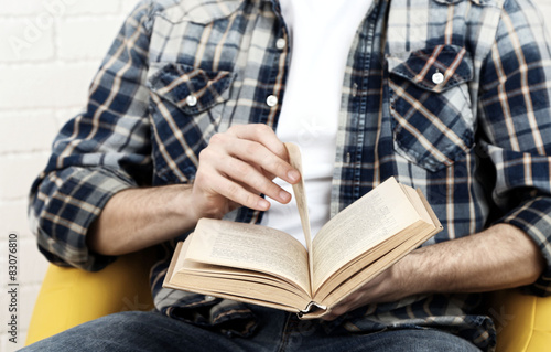 Young man reading book, close-up, on light background