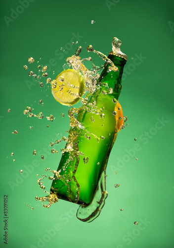 Bottle of fruit beer with splash, on gree