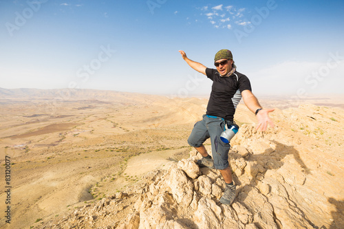 Man standing desert mountain cliff edge.