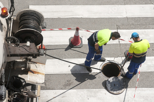 workers moves the manhole cover to check the sewer line