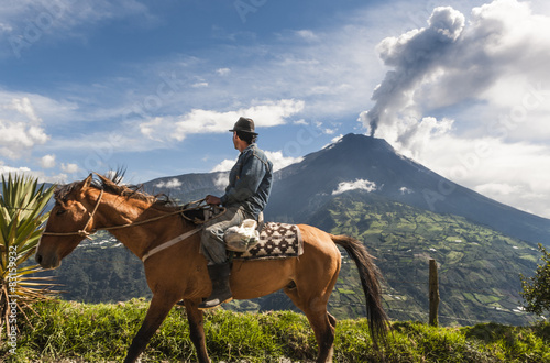 Unrecognizable farmer on a horse front of volcano Tungurahua