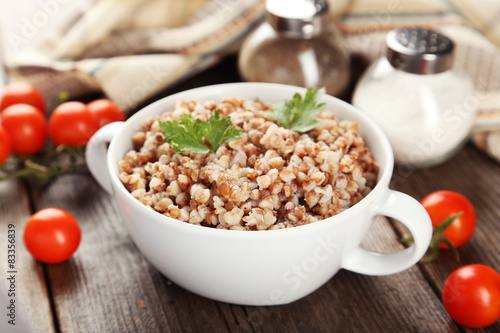 Buckwheat in bowl on brown wooden background