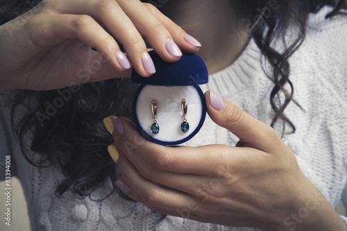 Gold earrings with blue topaz in women's hands