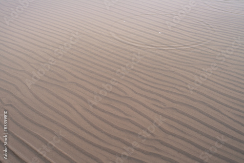 Wave-shaped sand and shallow water on beach in winter
