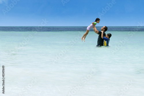 Man throwing her daughter on beach