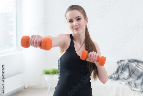 Active sportive athletic woman boxing dumbbells pumping up