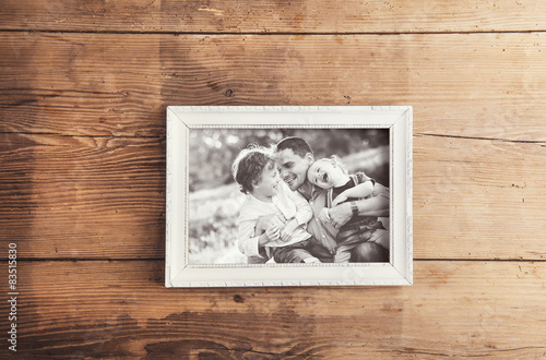 Picture frame with family photo laid on a wooden background.