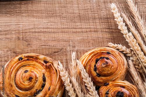 Golden wheat ears sweet raisin rolls on oaken wooden board food 