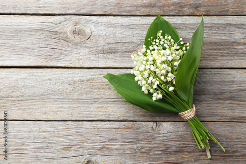 Lily of the Valley with leaves on grey wooden background