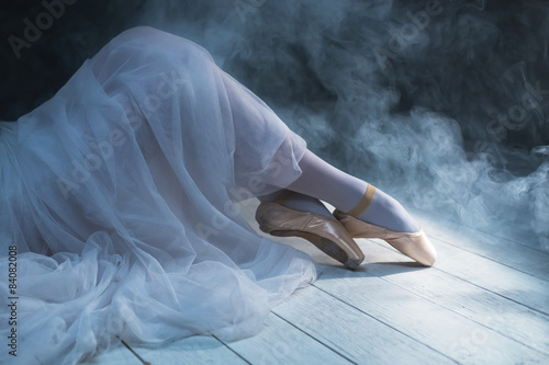 The feet of a sitting ballerina in smoke. Dancing legs.