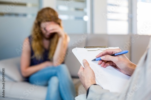 Psychologist talking with her depressed patient and taking notes