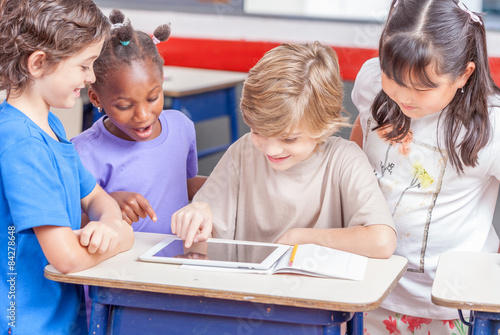 Multi ethnic primary classroom. Schoolchildren playing with tabl