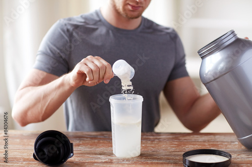 close up of man with protein shake bottle and jar