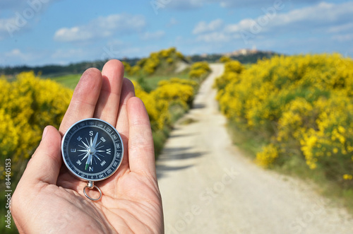 Compass in the hand against rural road