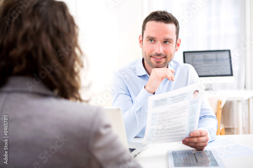 Young attractive employer analysing resume of woman