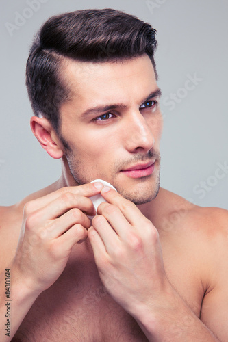 Man cleaning face skin with batting cotton pads