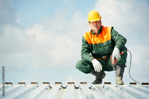 Worker builder roofer at metal profile work